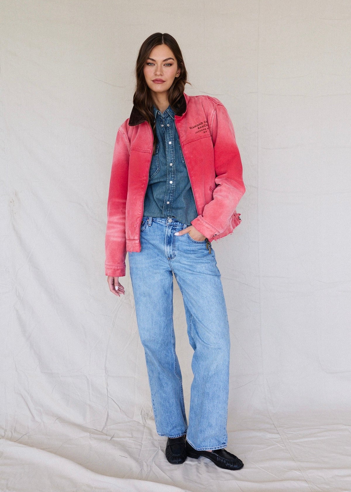 Faded Red | Person wearing a pink jacket, blue shirt, and jeans on a plain background