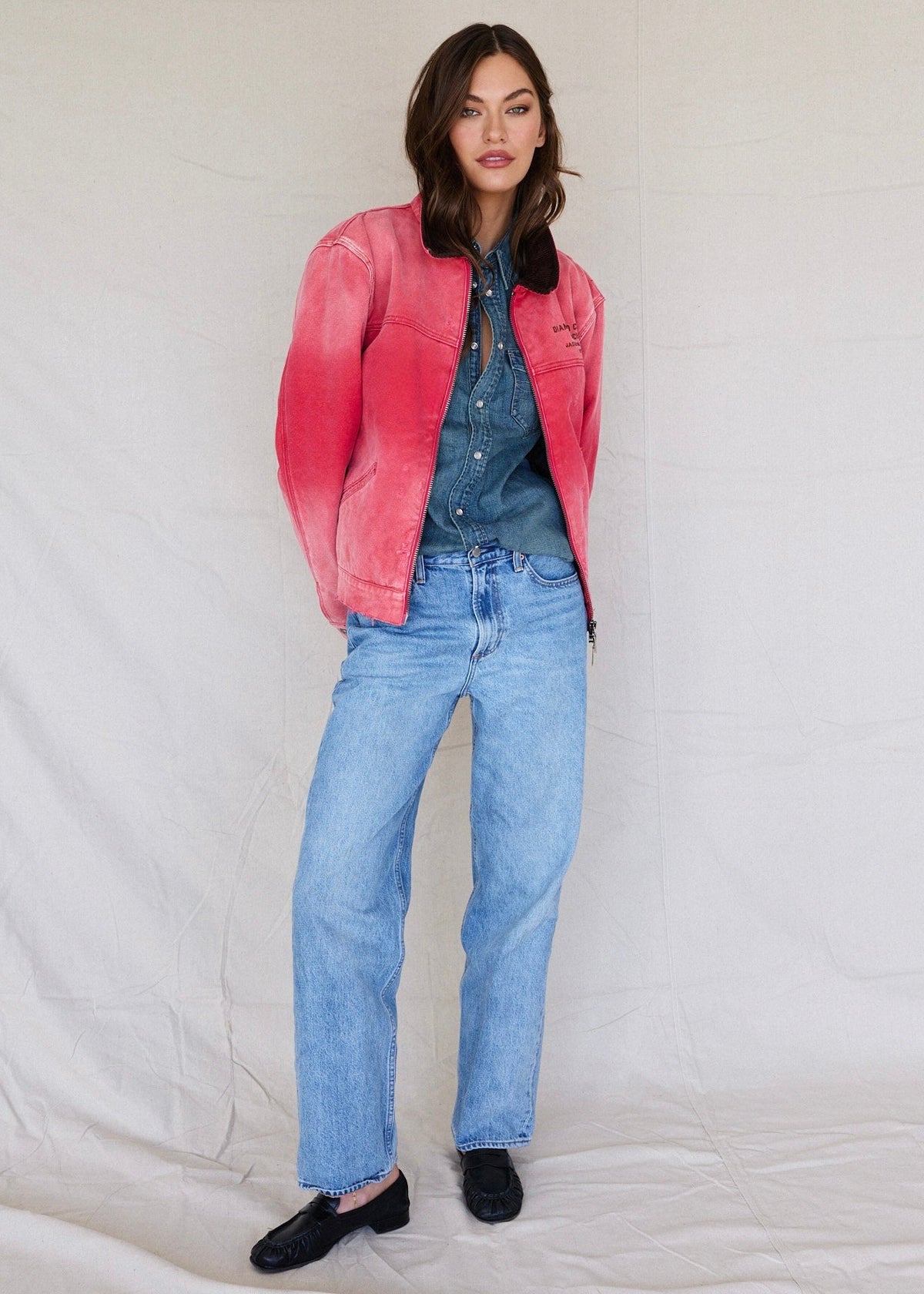 Faded Red | Woman wearing a pink jacket, denim shirt, and jeans on a white background