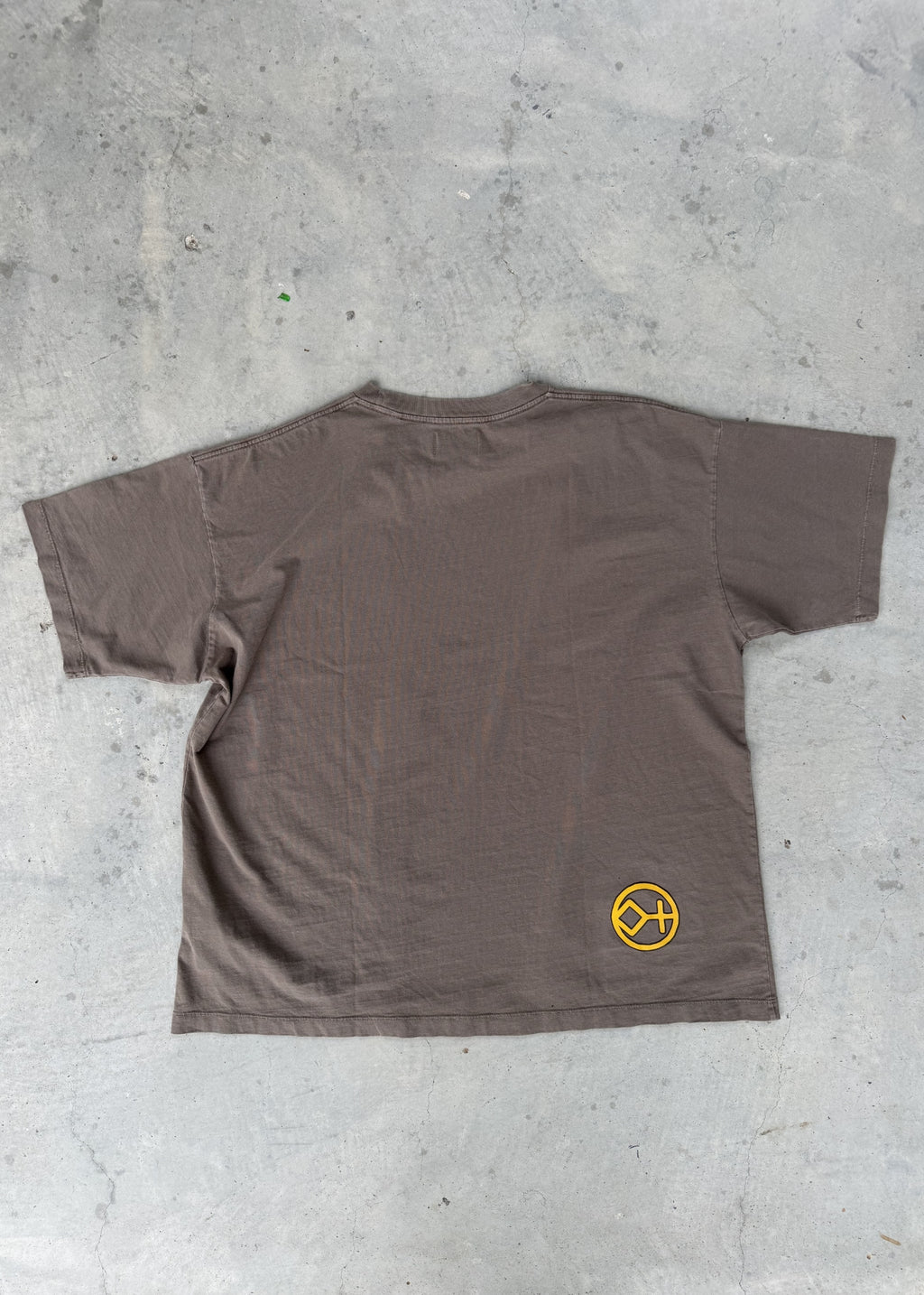 Vintage Brown | Brown t-shirt with a yellow logo on a concrete floor