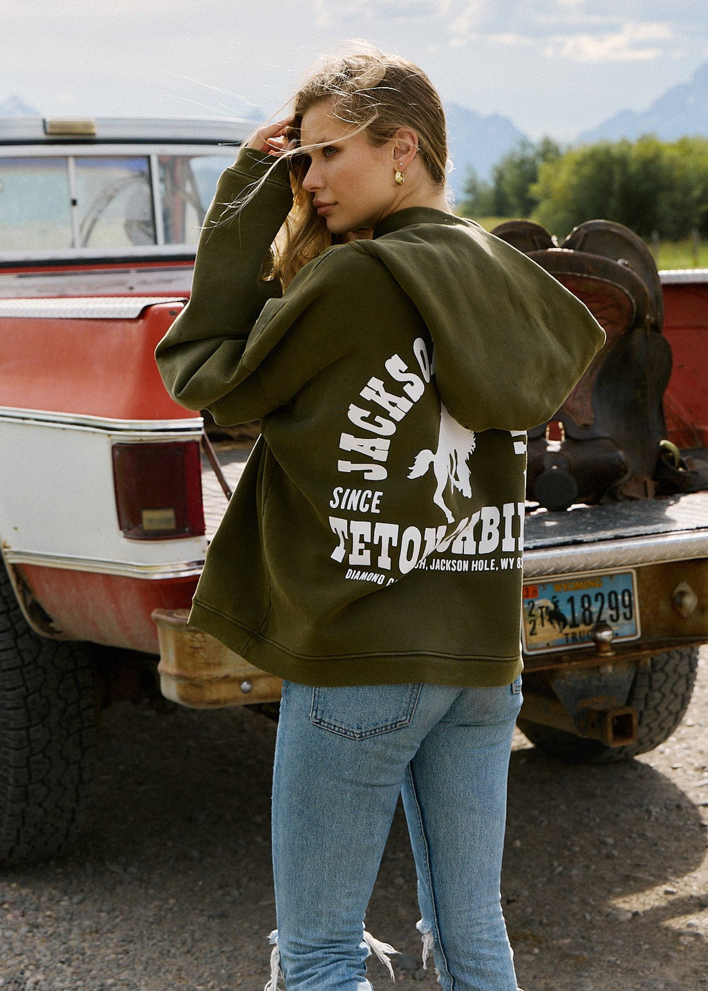 Army Green | Person wearing a green hoodie with branding in front of a vintage truck