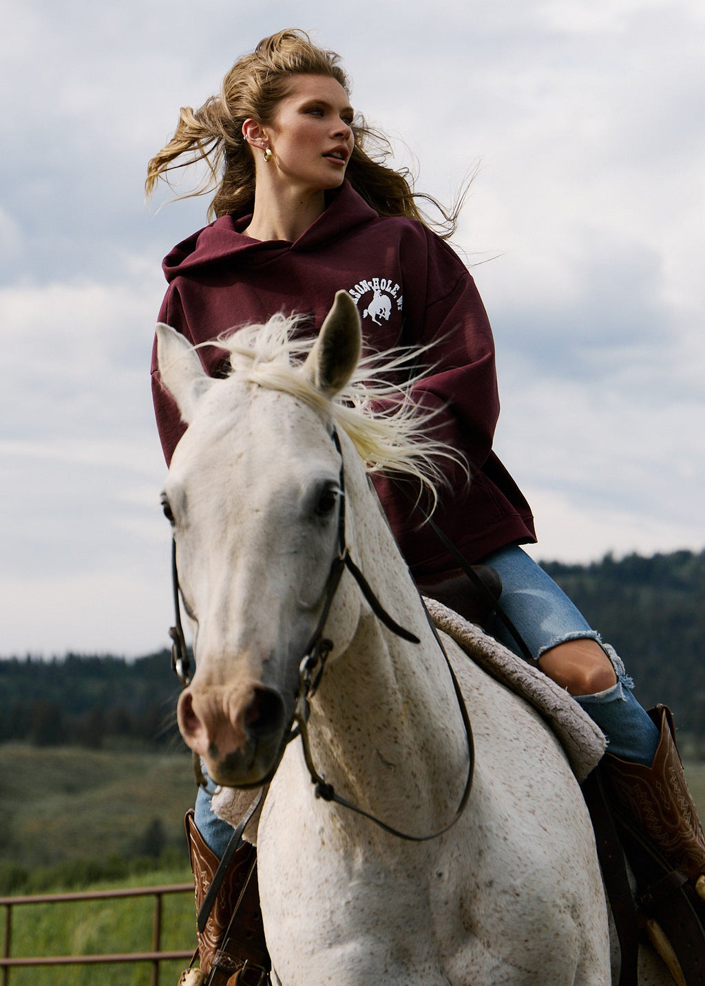 Burgundy | Woman riding a white horse in a scenic outdoor setting
