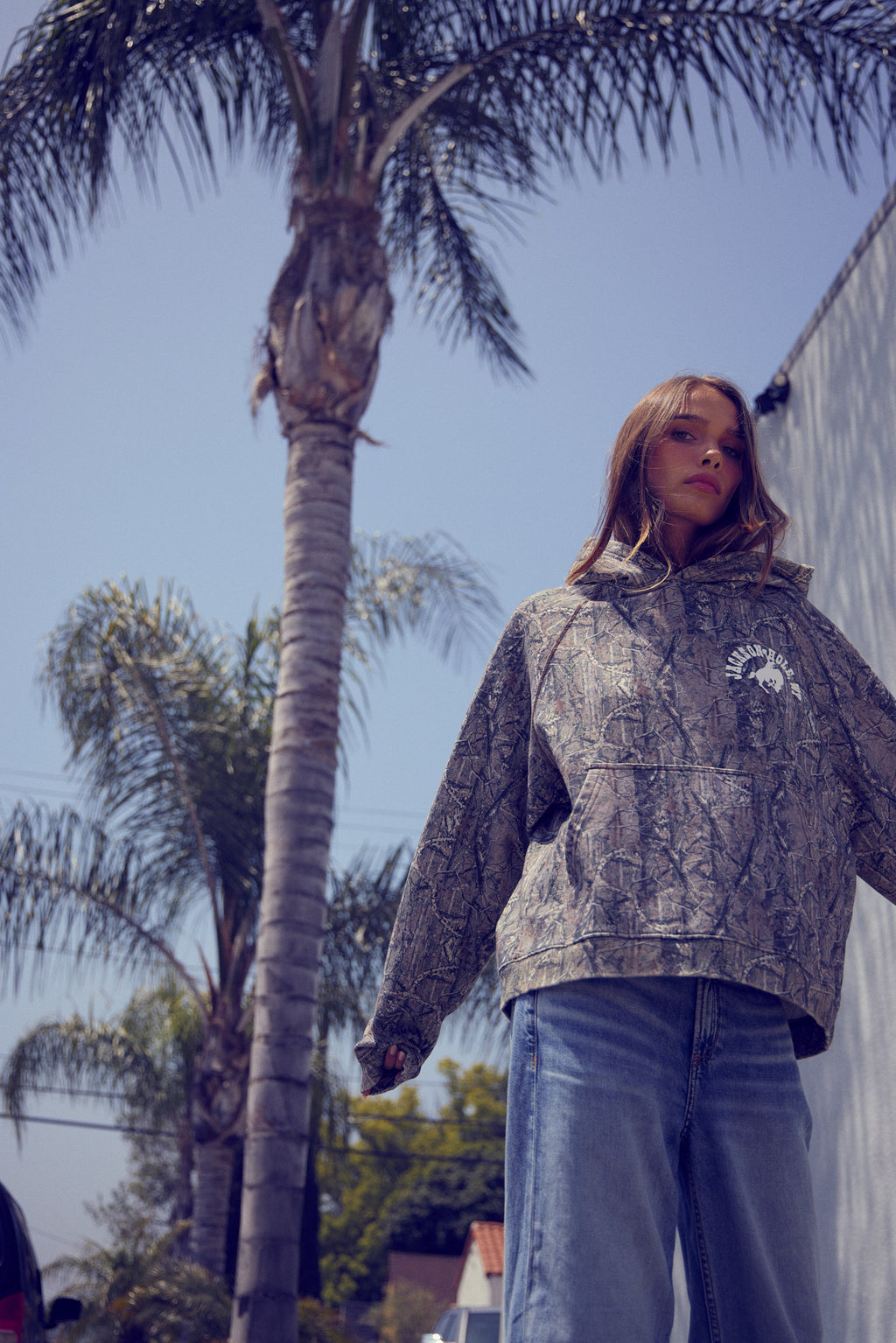 Sage Brush Camo | Person wearing a patterned hoodie with a palm tree and clear sky in the background