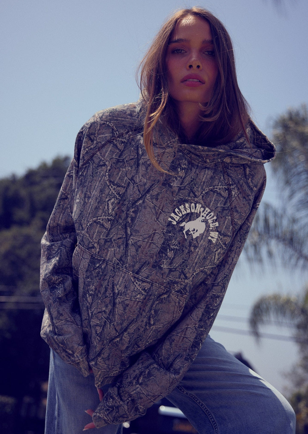 Sage Brush Camo | Person wearing a patterned hoodie with a logo outdoors