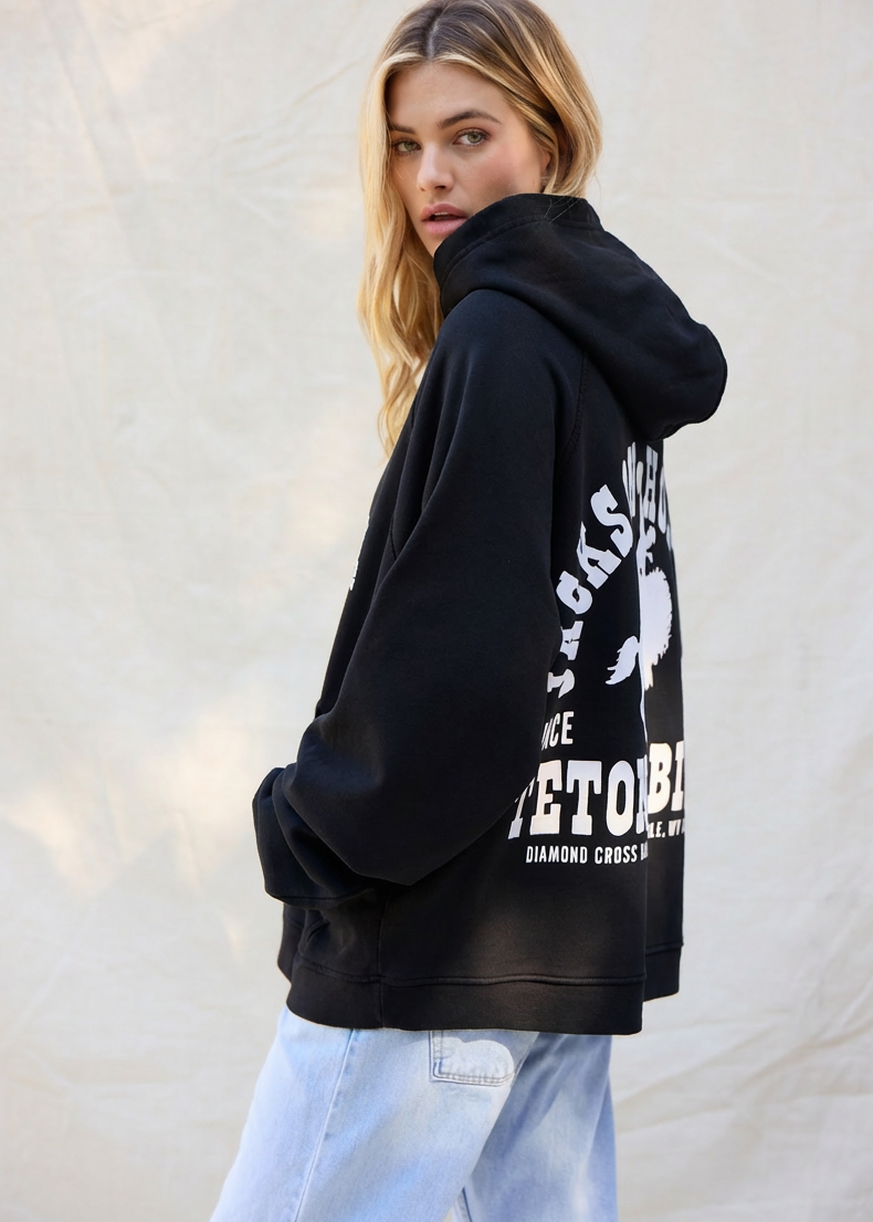 Sun Faded Black | Person wearing a black hoodie with white text on the back against a light background