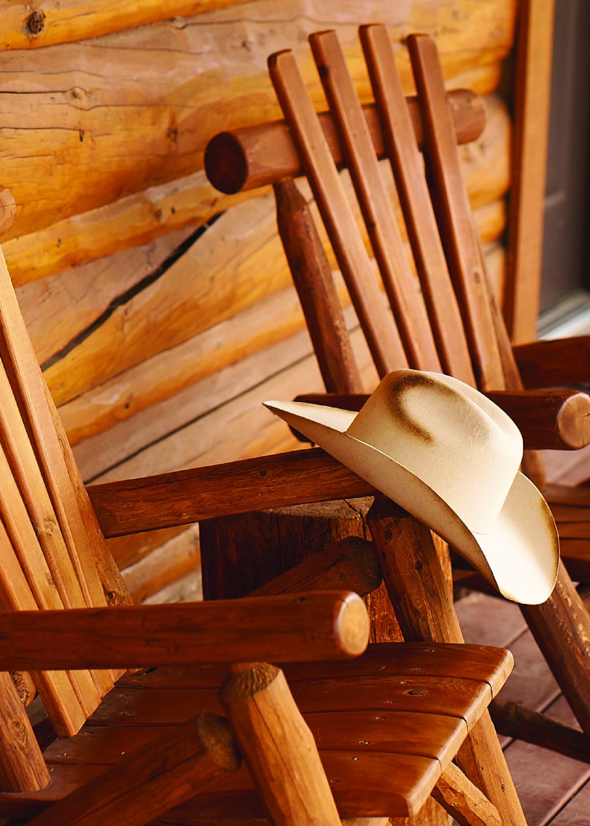 Cowboy hat on a log rocking chair on a cabin porch